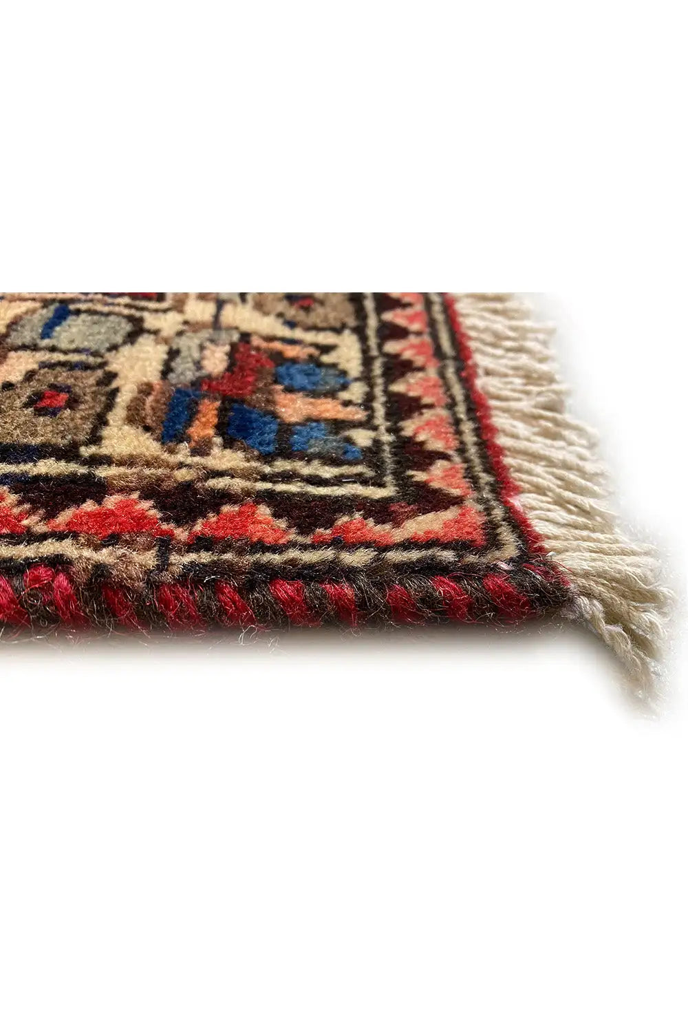 Rug edge with fringe and a colorful pattern on a red background