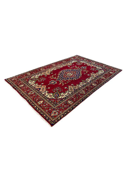 Red Oriental rug with a blue-and-gold ornamental border and central medallion, angled