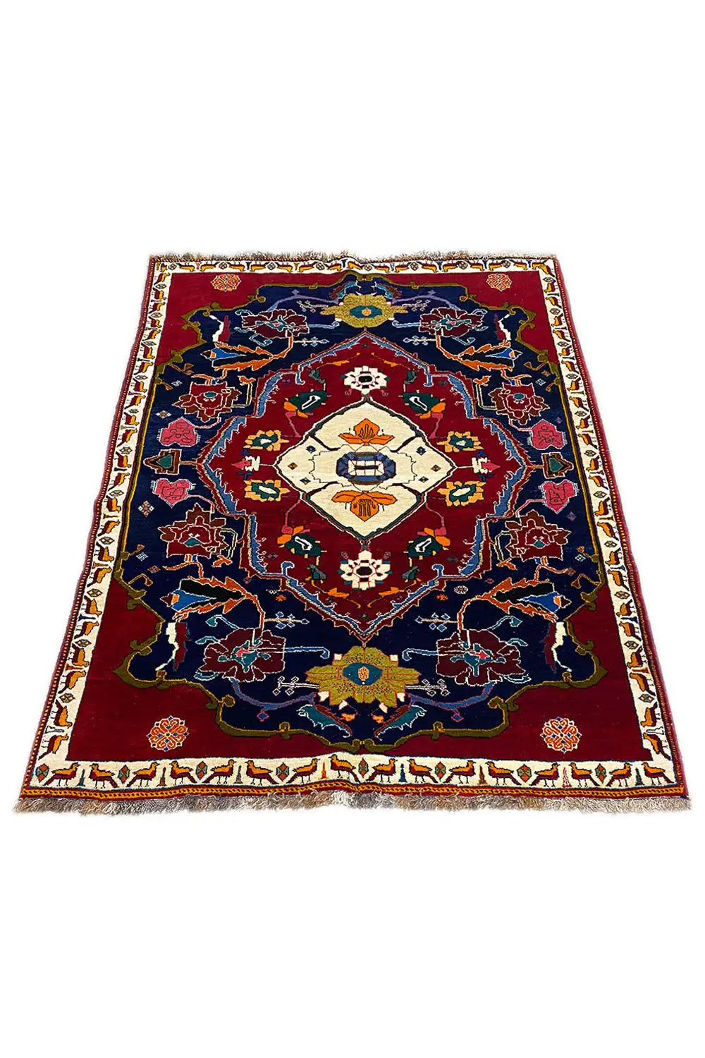 Rug from an angled perspective: red border, blue field, cream-colored medallion