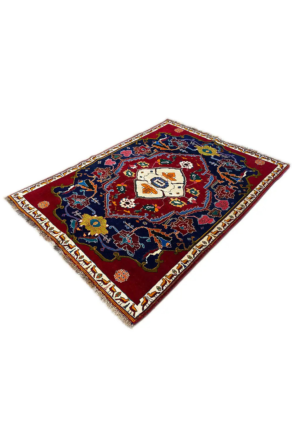 Carpet in an angled view: dark blue patterned field with a red border and cream-colored central motif