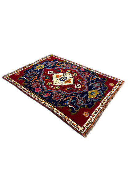 Rug in angled view: dark blue ornamental field, red border, square central motif