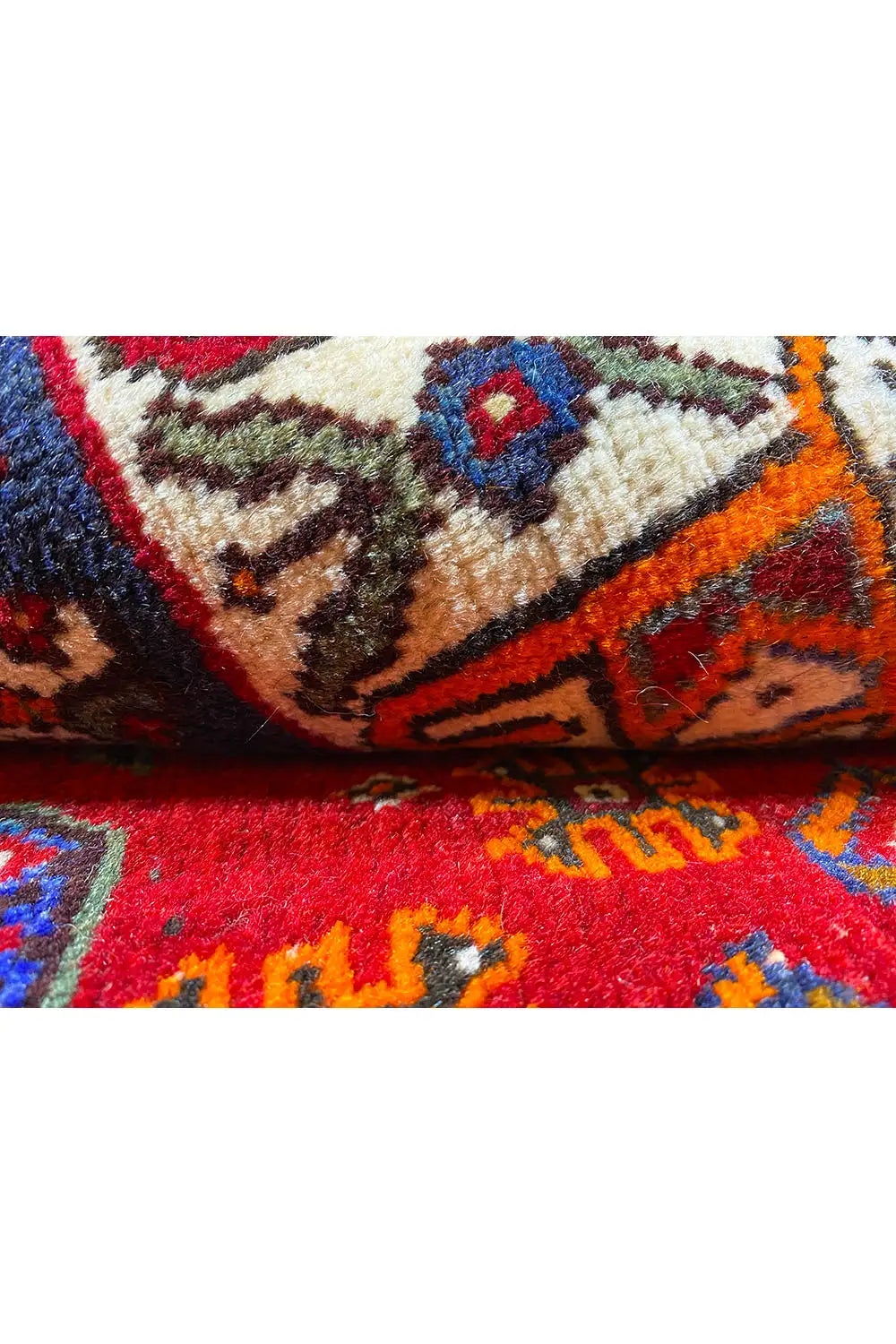 Detailed view of carpet pile with a red background, blue-green motifs and textures.