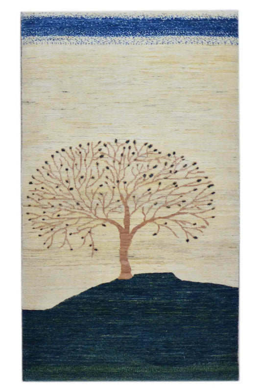 Gabbeh rug with a tree motif, cream-colored field, dark blue lower edge, and border strips.