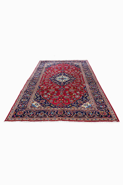 Rectangular rug with a red background, blue border, and multicolored ornaments