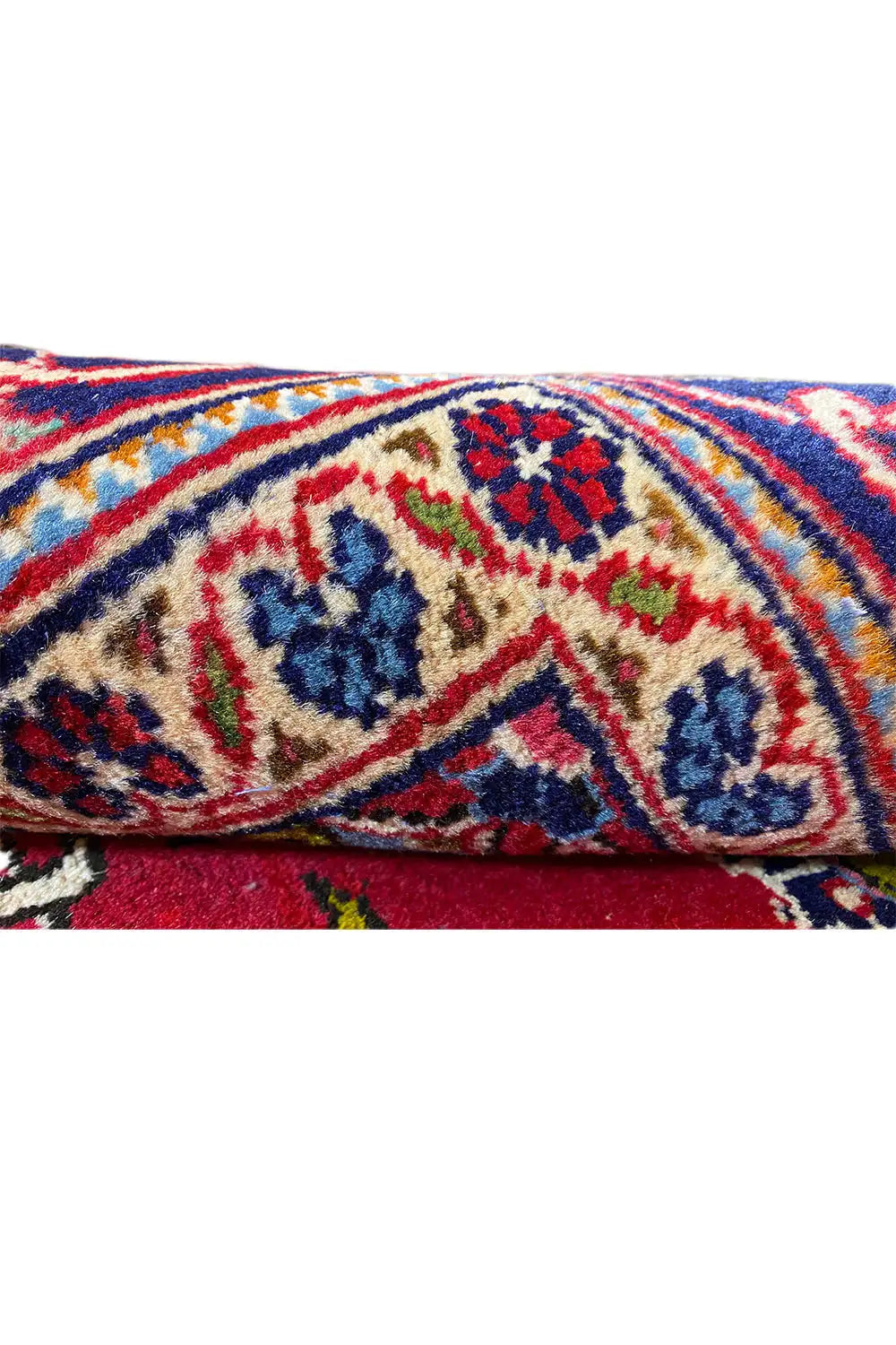 Rug detail: colorful ornamental border on a red background, visible pile