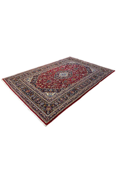 Oriental rug with a red central pattern and dark blue-and-gold border, photographed at an angle