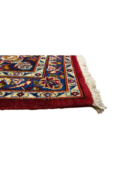 Corner detail of an Oriental rug: red border, multicolored patterns and fringes