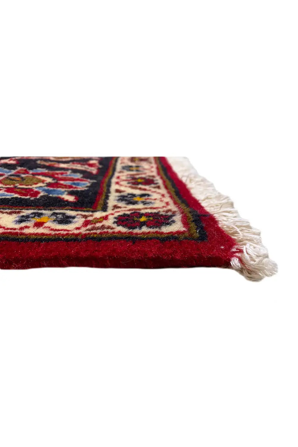 Corner detail of an oriental rug with fringes, a red background, and ornaments.