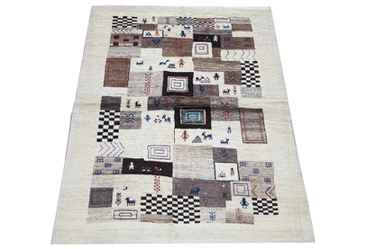 Gabbeh rug with a light background and a patchwork pattern in brown, blue, and black.