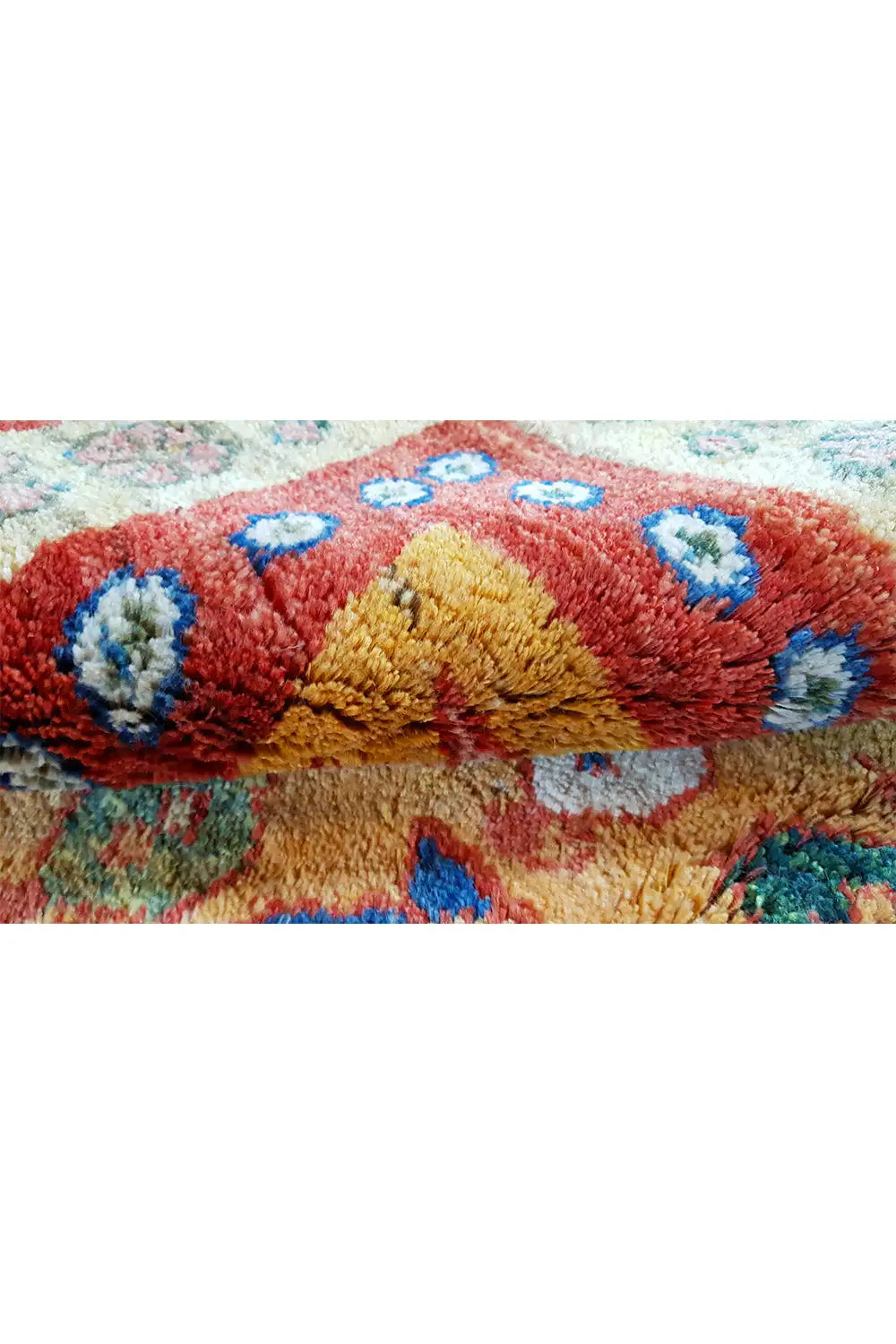 Gabbeh rug detail with red pile, yellow accents, blue medallions, and fringe