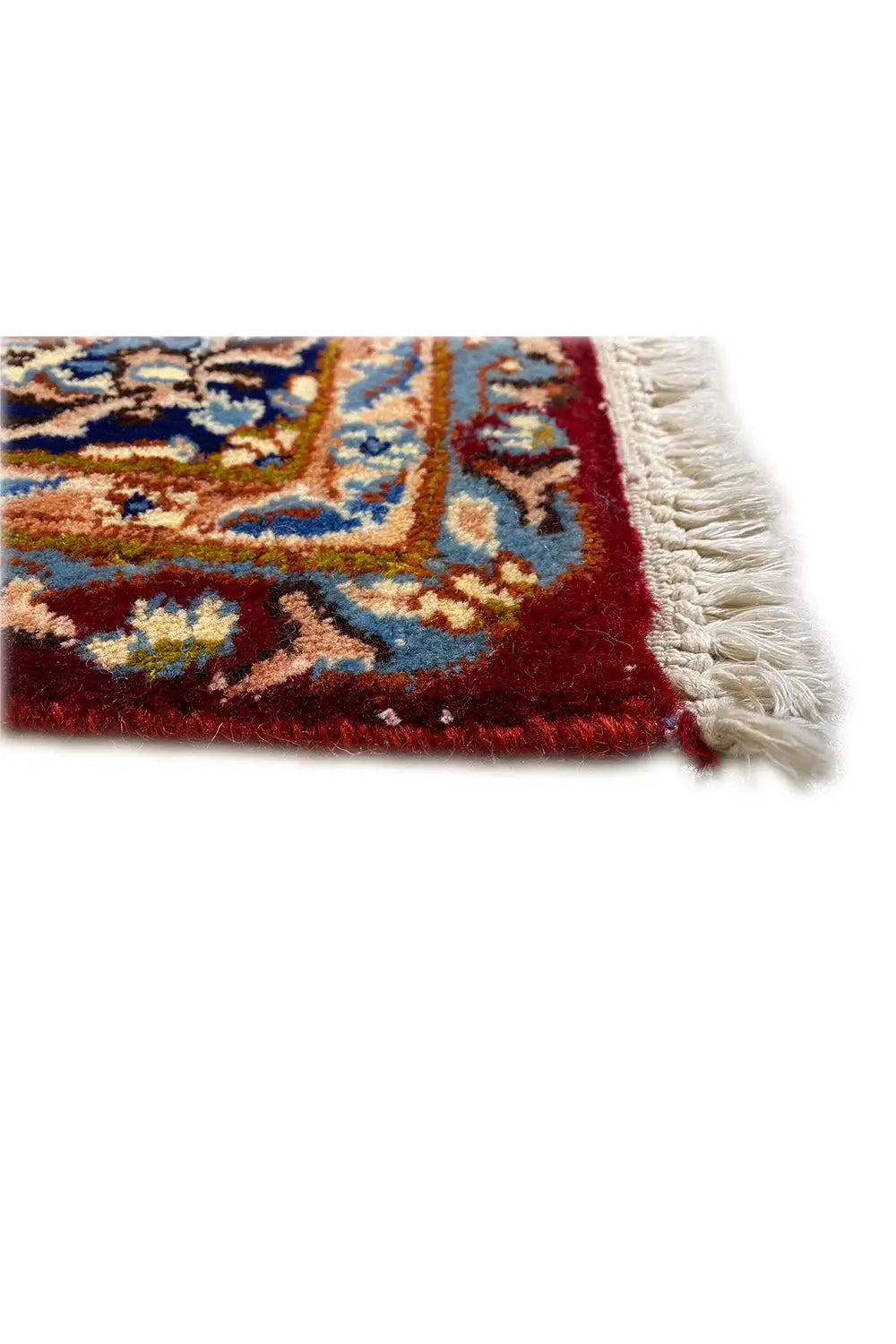 Kerman carpet corner: red pile, blue-and-gold patterns, and fringed edging