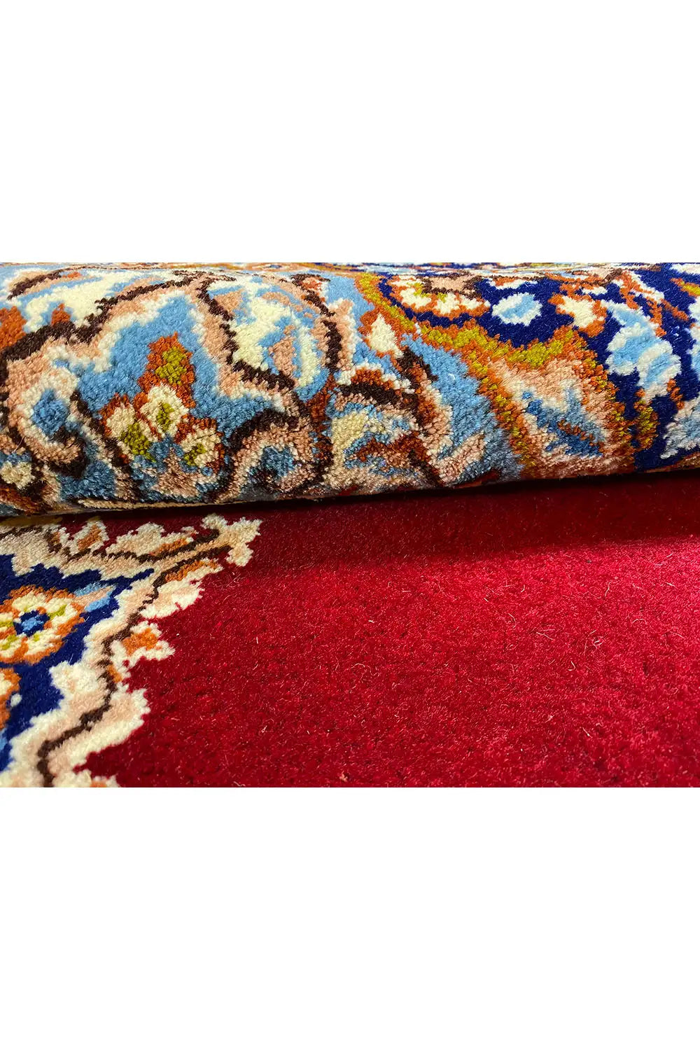 Close-up of a Kerman rug: red pile with blue and gold ornaments and a woven texture