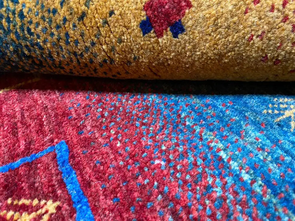 Gabbeh rug close-up: dense pile with a red-and-blue pattern and subtle color nuances