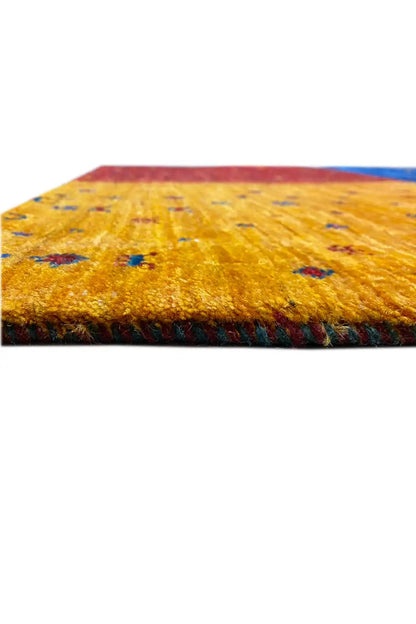 Close-up of a Gabbeh rug: yellow pile with red and blue accents, appearing hand-knotted