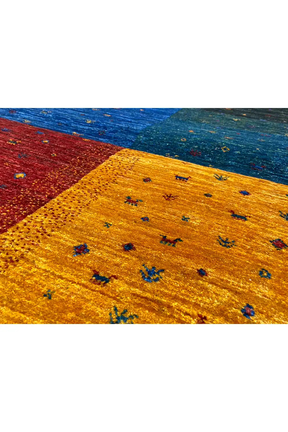 Close-up of a Gabbeh rug: yellow area with colorful flecks, next to blue and green