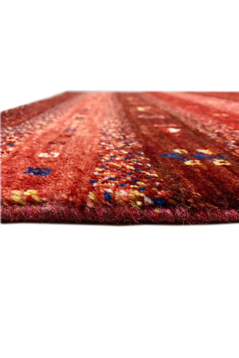 Gabbeh rug detail, reddish-brown pile texture with colorful accents and a finished edge