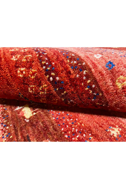 Gabbeh rug detail, reddish-brown pile with colorful motif areas and border edge
