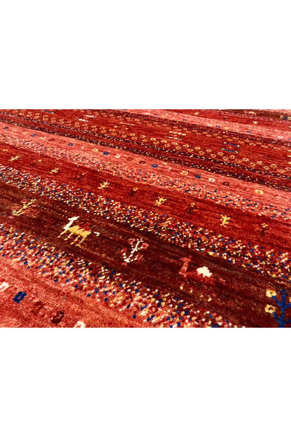 Close-up of a Gabbeh rug, red-brown stripes with golden and blue symbols