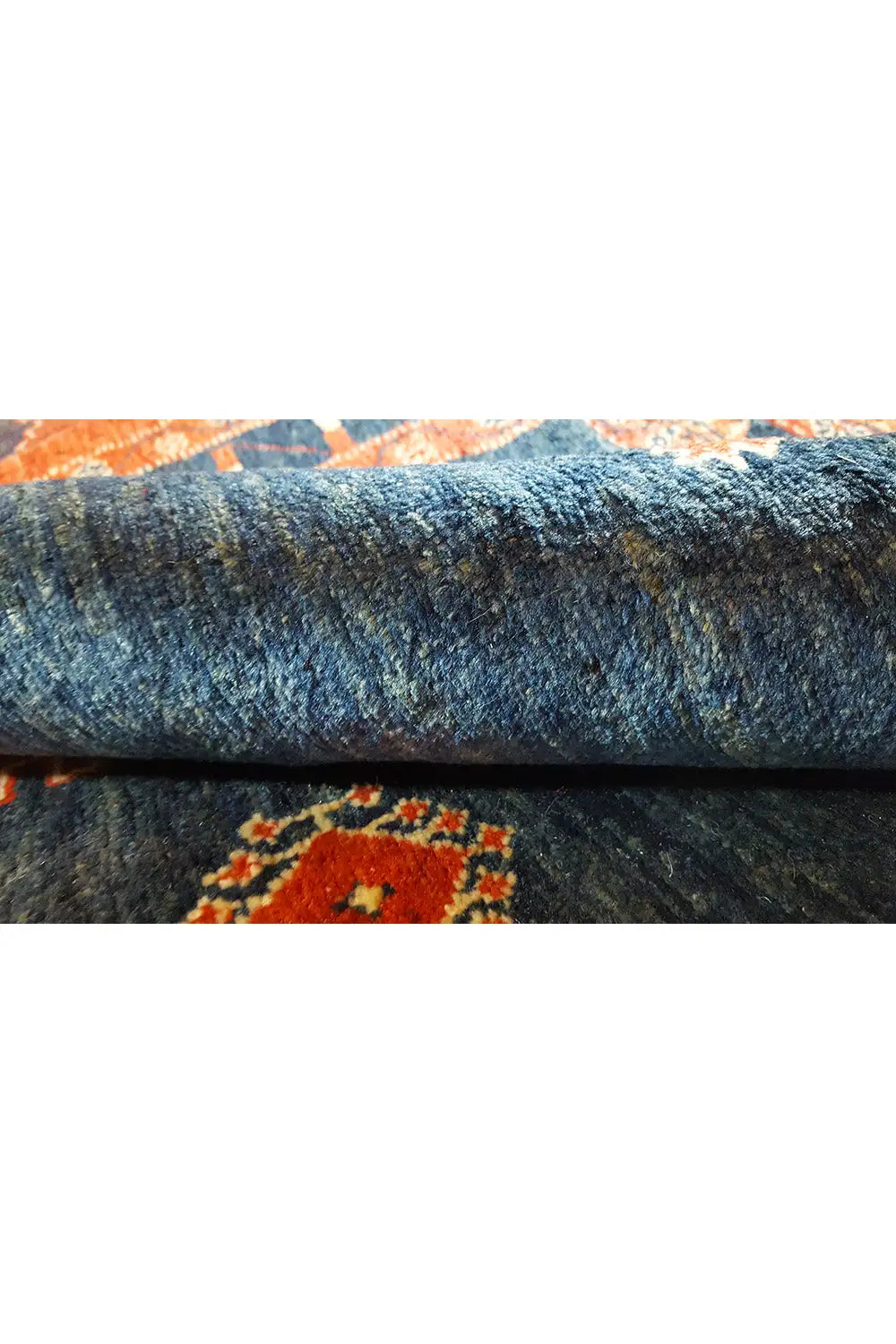 Side view of the carpet: dense blue texture with remnants of colored patterns along the edge