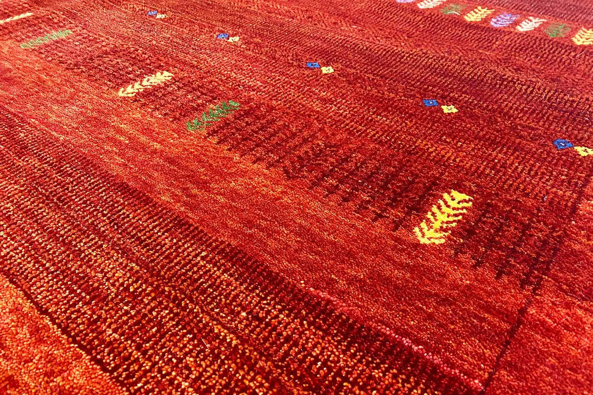Close-up of a Gabbeh rug: fine red weave with colorful dot and stripe patterns