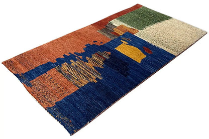 Gabbeh rug at an angle, geometric bars in blue, orange, and beige