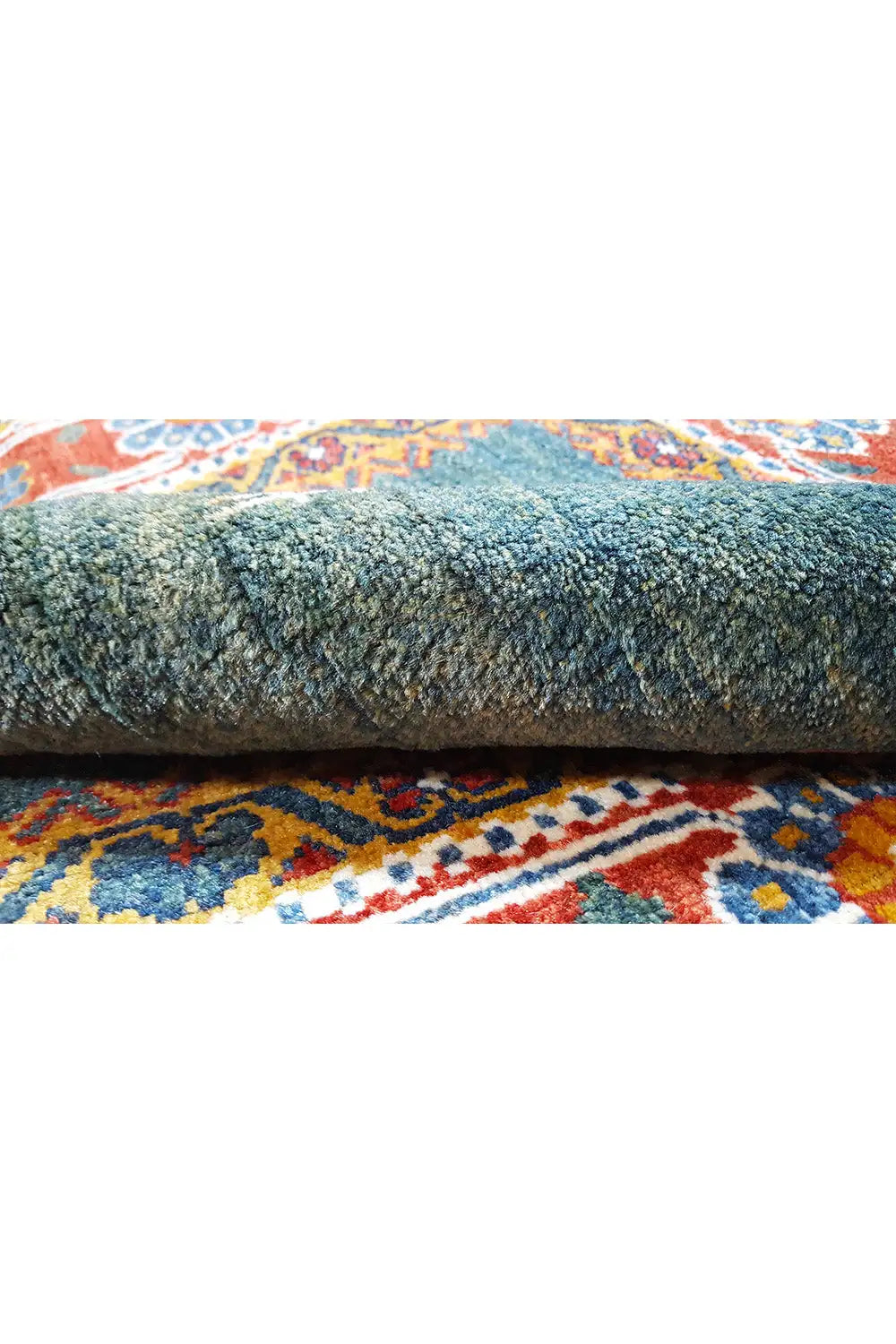 Rug detail: dense pile in petrol green with a multicolored border and fringes