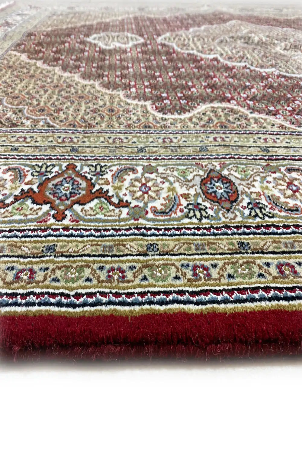 Tabriz carpet detail: multi-row borders with red and white patterns, fringed edge