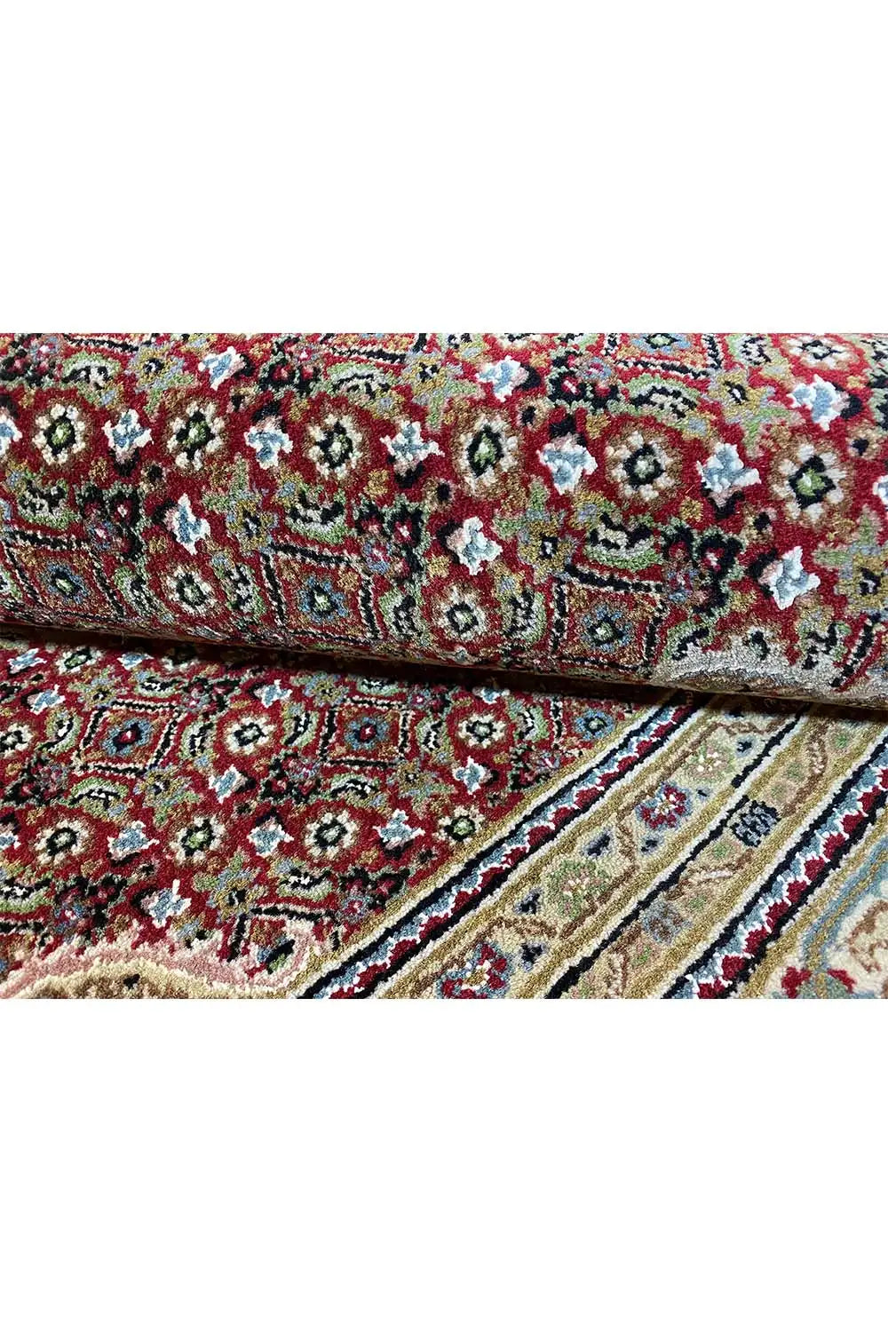 Tabriz carpet detail: dense floral pattern in red, green, and beige along a border