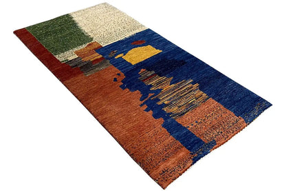 Gabbeh rug at an angle, geometric color blocks in blue, rust red, and beige-green