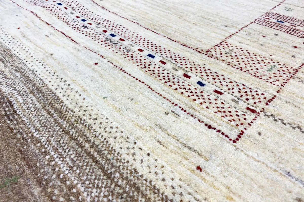 Lori Gabbeh rug detail: fine decorative border with red and blue dots on a light beige background