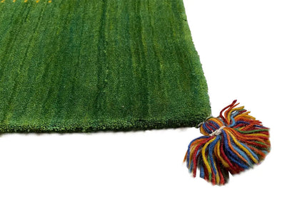 Green Gabbeh rug: close-up with colorful tassels and dense pile