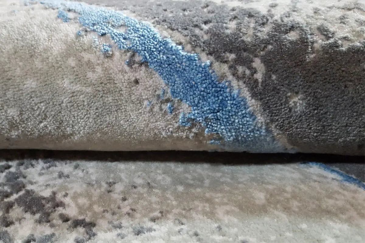 Beach carpet edge detail: gray pile with a blue contour line and a bound edge.