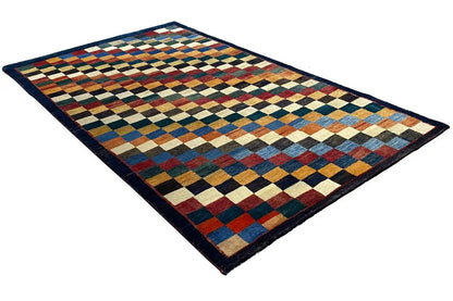 Gabbeh rug “Lori” lying at an angle, multicolored diamond-check pattern with a dark border