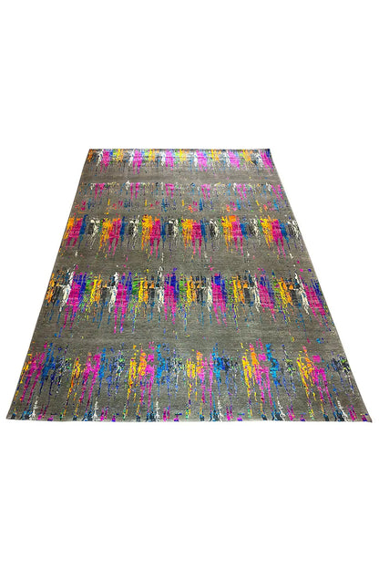 Designer rug displayed at an angle with colorful lines and spots on a gray background.