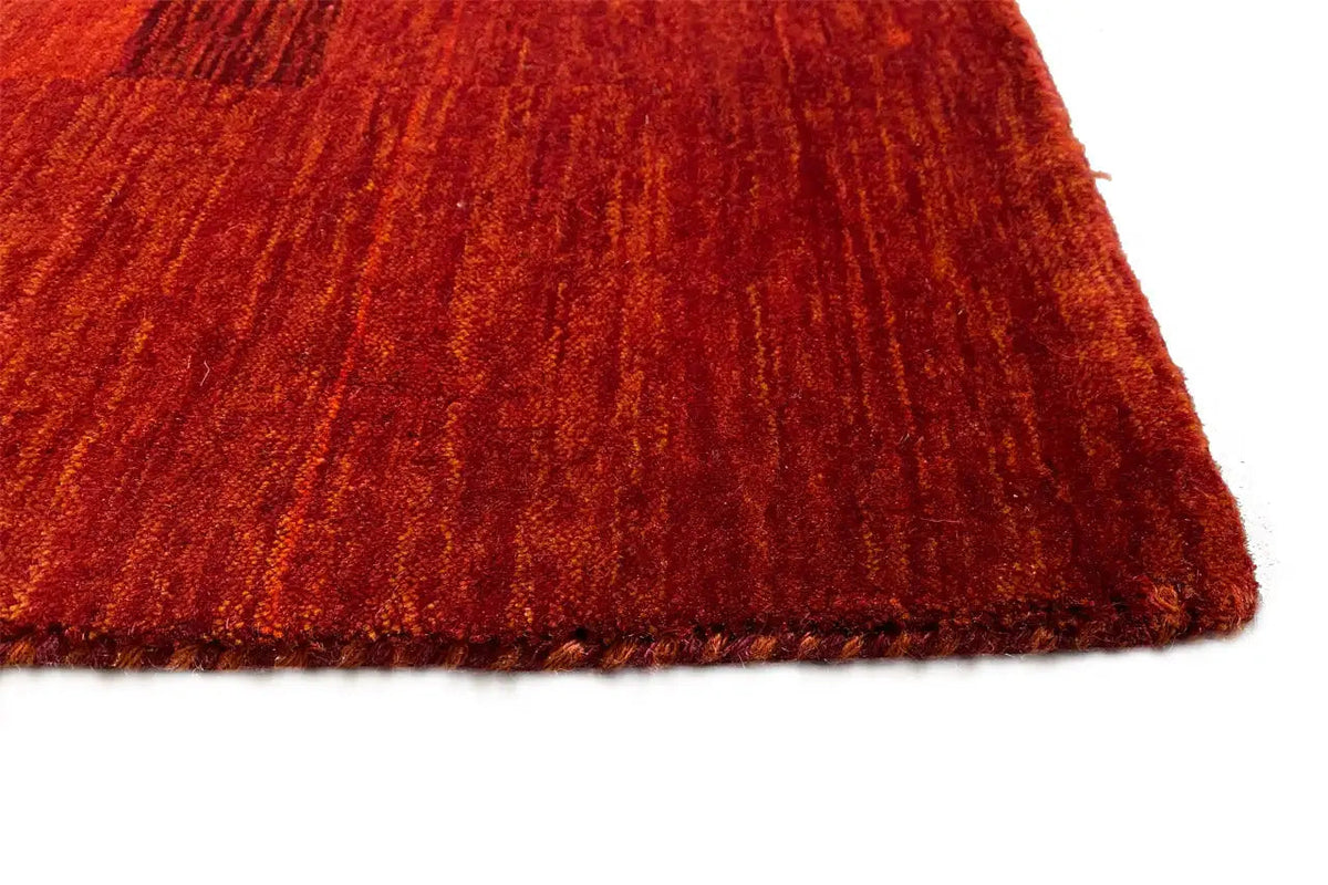 Gabbeh rug with short pile fringes, vivid red-orange, edge view