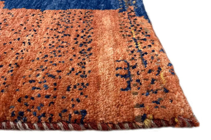 Gabbeh rug detail at the edge: brown-orange area with a blue pattern and fringes