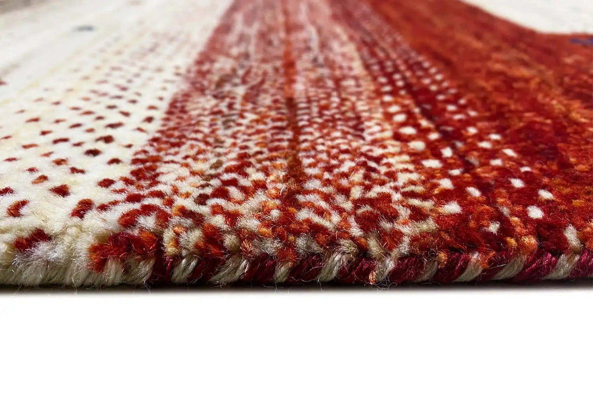 Gabbeh rug close-up: short fringe along the edge, red and cream-colored pile texture