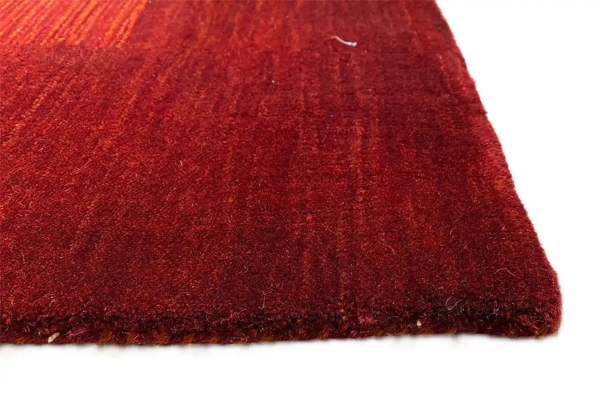 Red Gabbeh rug, corner view with a fine pile and characteristic woven texture.