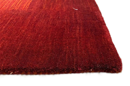 Red Gabbeh rug, corner view with a fine pile and characteristic woven texture.