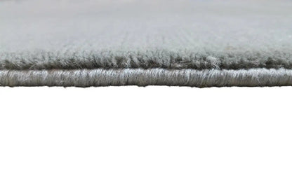 Carpet edge with short, gray pile and a visible seam along the edge.