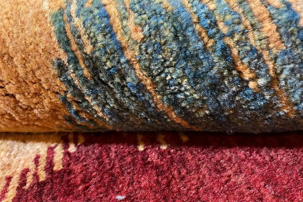 Gabbeh rug fabric detail: blue zigzag pattern between beige and red fibers