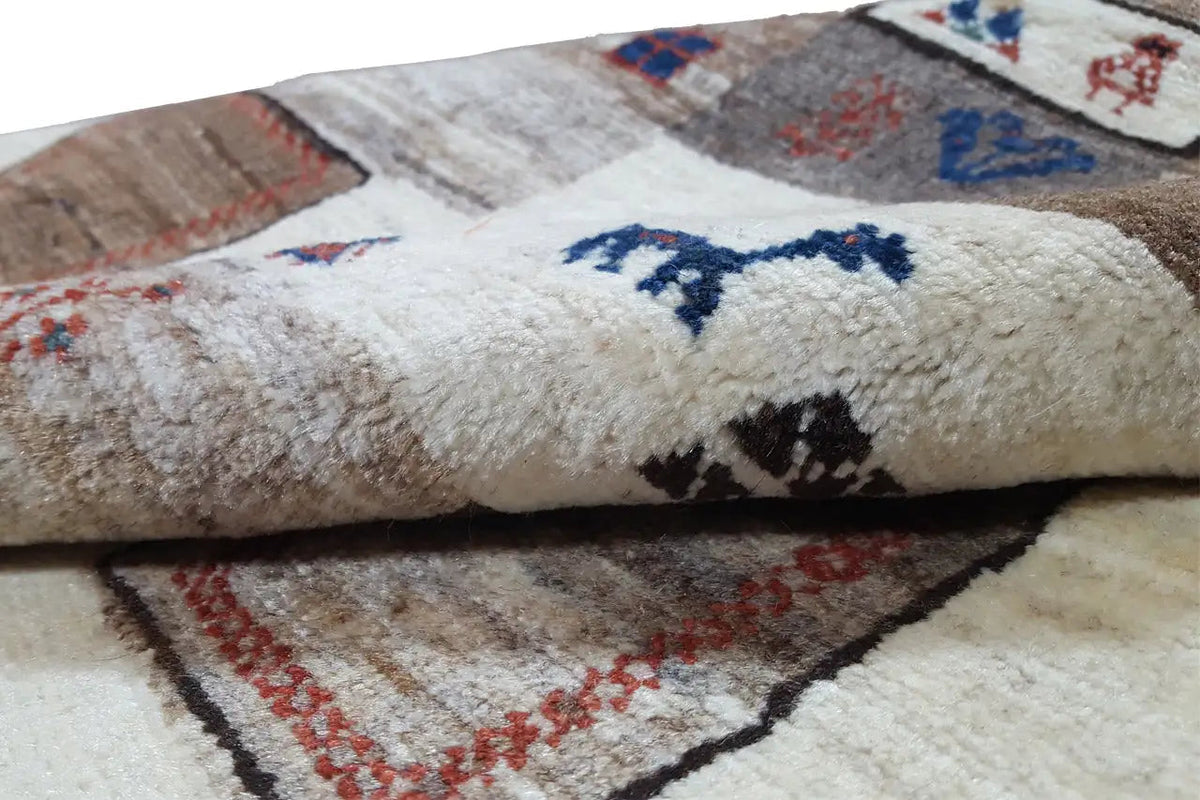 Gabbeh rug: dense virgin wool pile, light surface with blue color blocks.
