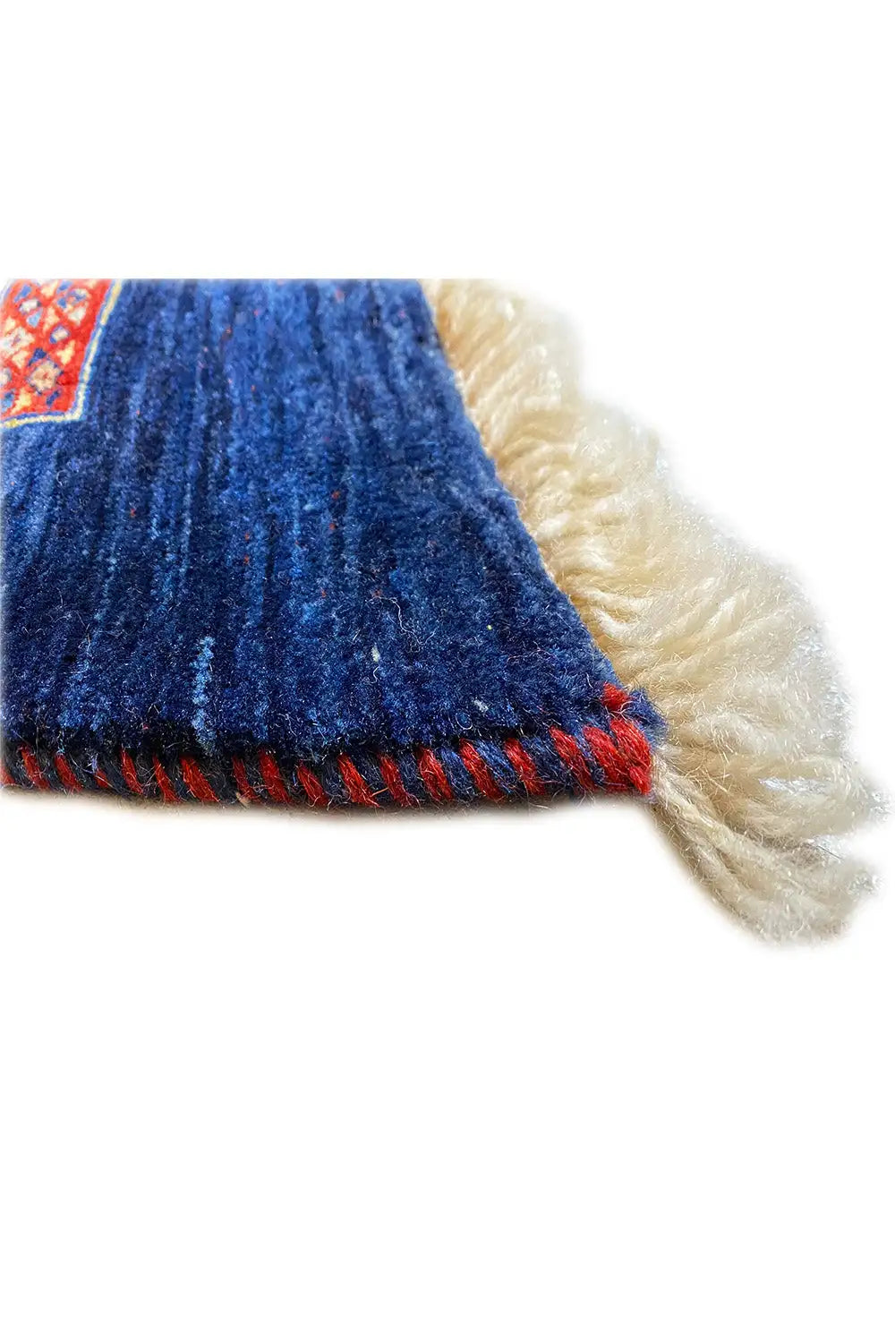 Carpet edge with blue pile, red fringe trim, and beige backing pile