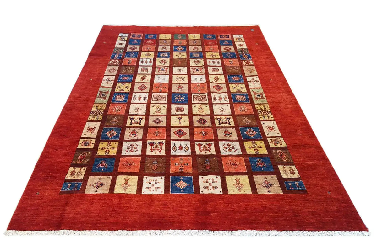Rug with a red border and a square patchwork pattern in blue, beige, and red
