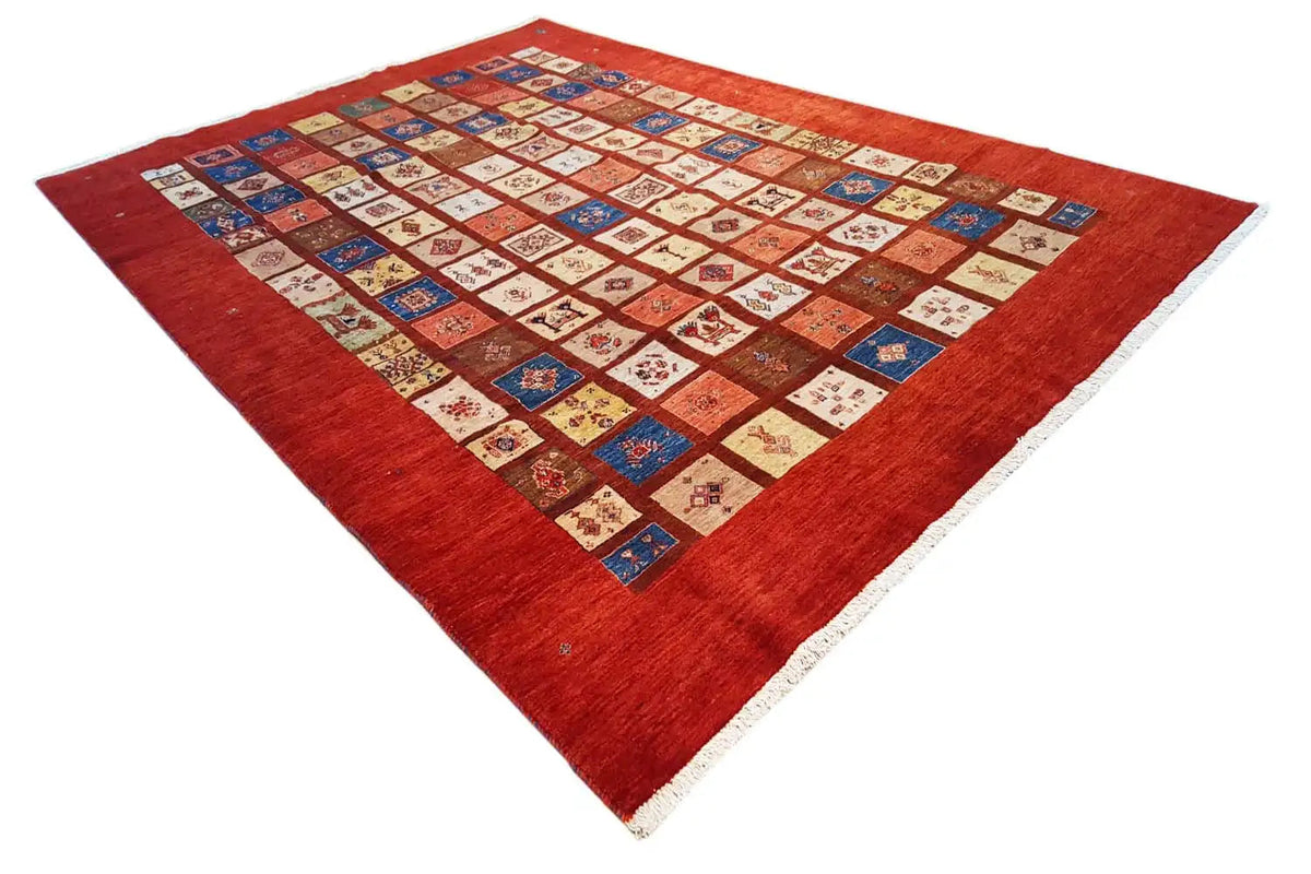 Rug with red pile and a central patchwork pattern in blue, beige, and red