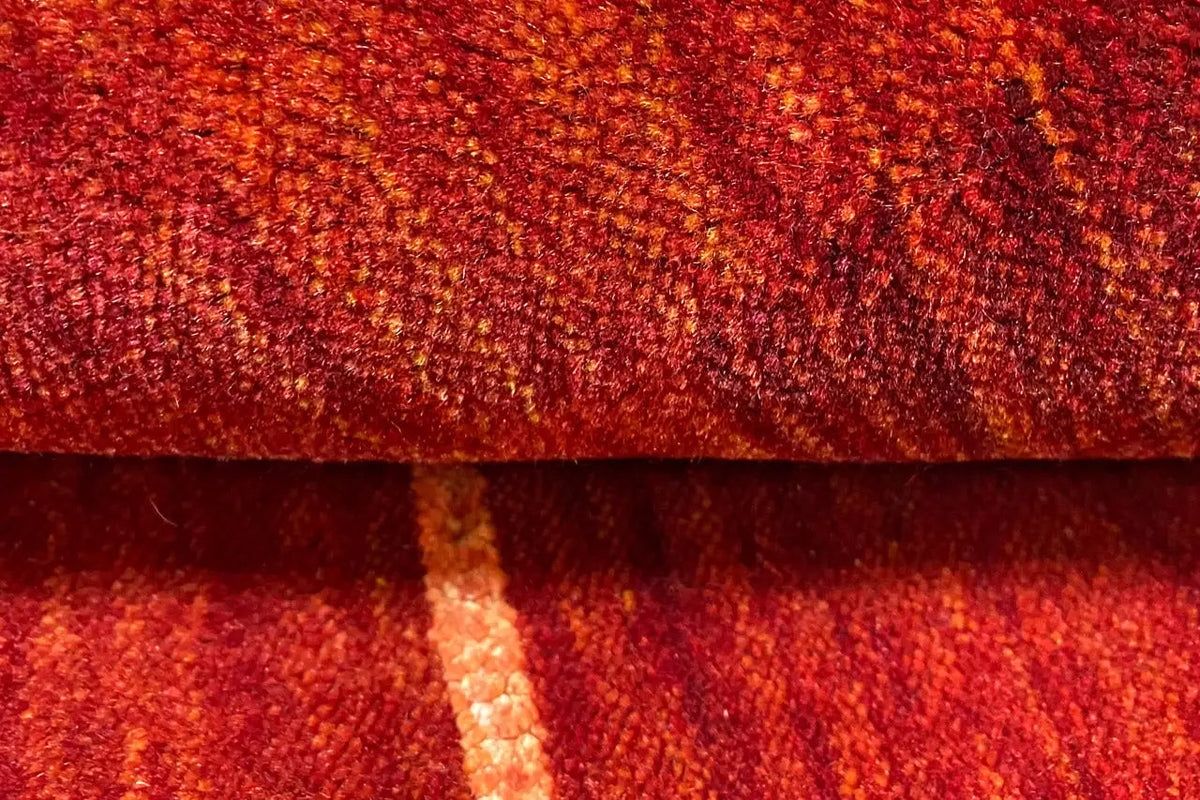Gabbeh rug with a reddish gradient and textured pile, close-up