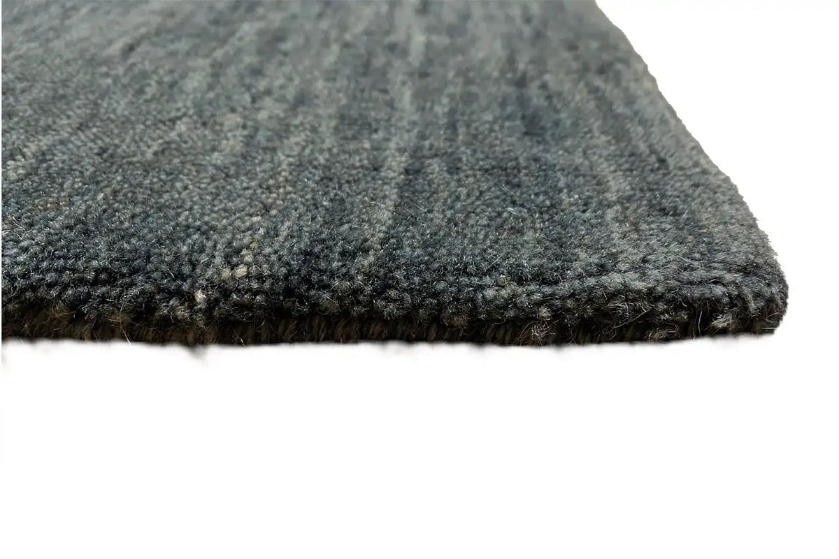 Corner view of a dark blue-gray carpet with a short, dense pile