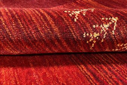 Red Gabbeh rug with a striped texture and gold-colored ornament detail.