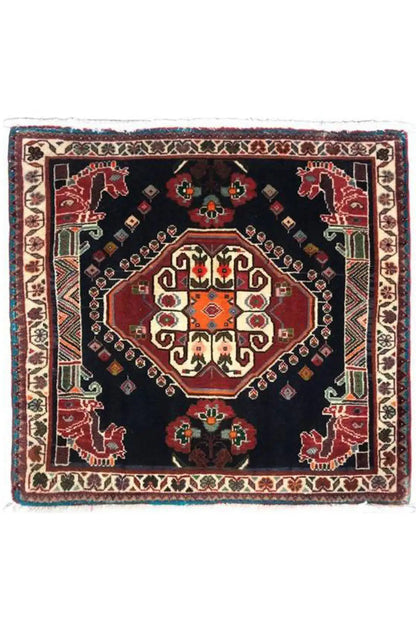 Square Oriental rug with a dark blue background, red central medallion, and fringes