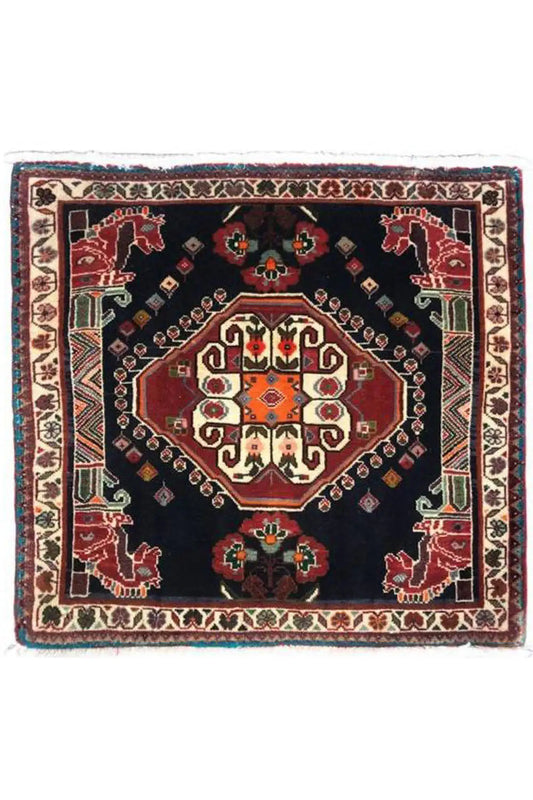 Square Oriental rug with a dark blue background, red central medallion, and fringes